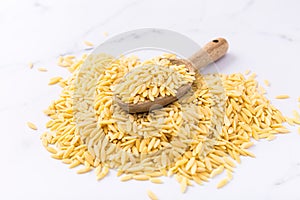 Raw orzo pasta (risoni) with wooden spoon