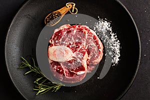 Raw osso buco on a black plate photo