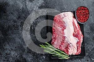 Raw outside Round roast beef meat cut on a marble board. Black background. Top view. Copy space