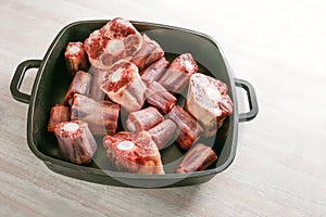 Raw oxtail pieces with bone in a black tray, gelatin-rich meat traditional for a slow-cooking stew or stock base for oxtail soup,