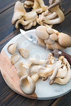 Raw oyster mushrooms slicing on marble cutting board