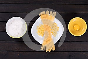 Raw pasta on a dark table, egg, flour.