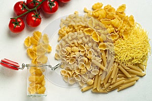 Raw pasta of different types durum wheat several different glass jar with cherry tomatoes top view