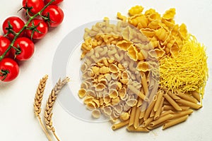 Raw pasta of different types; durum wheat varieties slightly different with cherry tomatoes top view