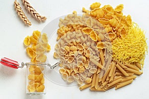 Raw pasta of different types; durum wheat varieties slightly different in a glass jar for storage; top view