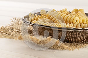 Raw pasta fusilli bucati on grey wood