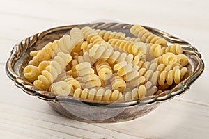 Raw pasta fusilli bucati on grey wood