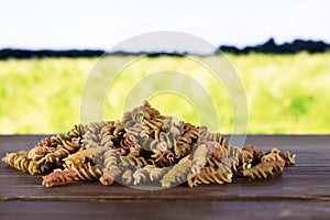 Raw pasta fusilli with field behind photo
