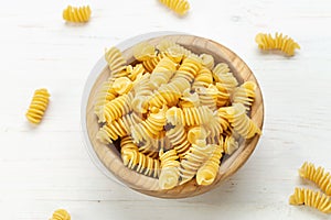 Raw Pasta Fusilli in Wooden Bowl on White Rustic Background