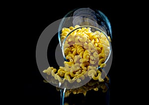 raw pasta in glass jar, wine glass. in bucket. raw pasta on black background. front view raw pasta, dropped from hand, place for