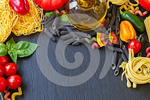 Raw pasta with ingridients on black board