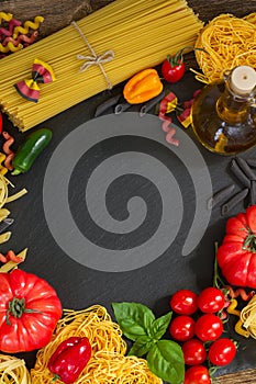 Raw pasta with ingridients on black board