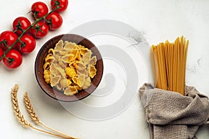 Raw pasta in a plate and long pasta tied in burlap with cherry tomatoes and spikelets of wheat