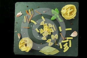 Raw pasta of various types and spices on a wooden table