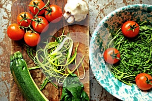 Raw pasta with zucchini and spinach pesto with tomatoes