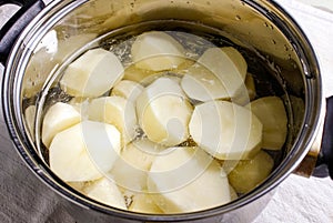 Raw peeled potatoes in a pot of water before cooking