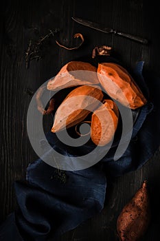 Raw peeled sweet potatoes on the wooden black table top view