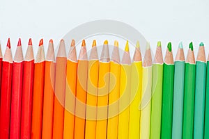 Raw of pencils paced in gradient from red to green over white background