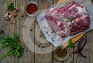 Raw piece meat of pork and spices marinade on wooden background. For steak, roasting, stewing. Space for text