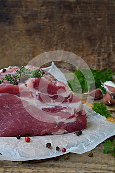 Raw piece meat of pork and spices marinade on wooden background. For steak, roasting, stewing. Space for text