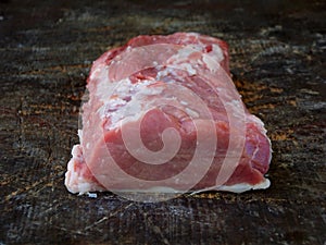 Raw piece of pork loin, breast on a wooden background.