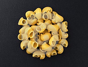 Raw pipe rigate pasta isolated on black background, top view