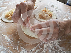 Raw pirozhki with cabbage in the cooking process.