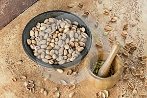 Raw pistachios in a bowl on the background surface, strewn with shells of nuts. Pistachio texture. Nuts.