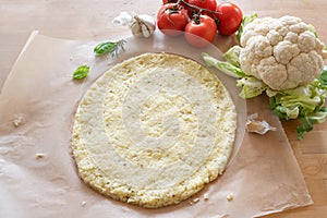 Raw pizza base from shredded cauliflower on baking paper, healthy vegetable alternative for low carb and ketogenic diet, copy