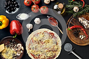 Raw pizza ingredients on black texture table background