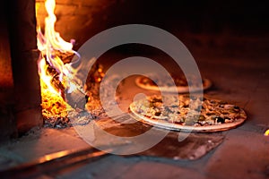 Raw pizza lay down stove with the fire on blade.