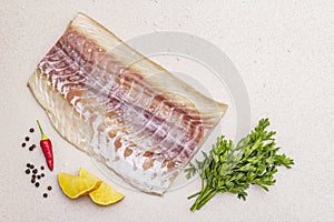 Raw pollock Pollachius virens fillet. Fresh fish for healthy food lifestyle. Lemon, parsley, sea salt, chili, black peppercorn