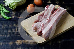 Raw Pork Belly sliced on cutting board dark background