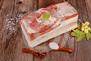 Raw pork belly with spices on wooden background