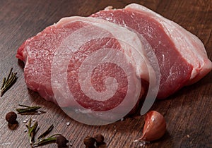 Raw pork chop steak and garlic, pepper on the brown wooden table background