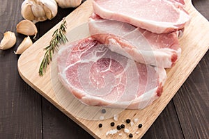 Raw pork chop steak and garlic, pepper on wooden background