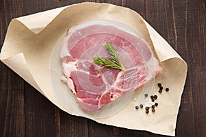 raw pork chop steak on paper and wooden background