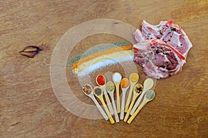 Raw pork chop steaks with meat fork, oil and spices for grill or cooking on rustic metal background, top view, border. Porco