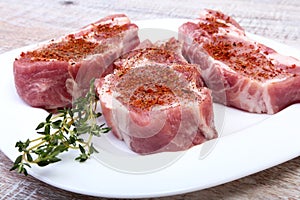 Raw pork chops, spices and rosemary on cutting board. Ready for cooking.