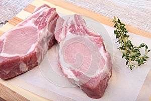 Raw pork chops, spices and rosemary on cutting board. Ready for cooking.