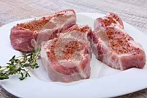 Raw pork chops, spices and rosemary on cutting board. Ready for cooking.