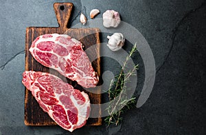 Raw pork cutlet chop for grill BBQ with herbs on wooden board, slate background, top view, copy spaces