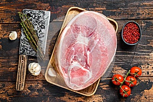 Raw pork ham cut on a wooden board. Leg meat. Dark background. Top view