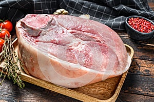 Raw pork ham cut on a wooden board. Leg meat. Dark background. Top view