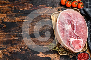 Raw pork ham cut on a wooden board. Leg meat. Dark background. Top view. Copy space