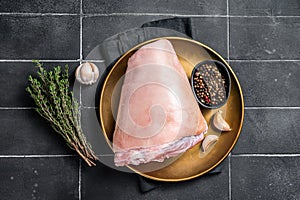 Raw pork ham hocks on a steel plate with herbs. Black background. Top view