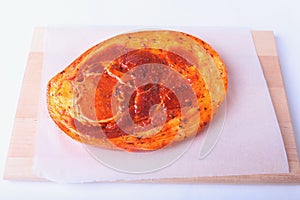 Raw Pork ham with spices and parsley leaves ready for BBQ grilling isolated on white background.