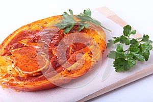 Raw Pork ham with spices and parsley leaves ready for BBQ grilling isolated on white background.