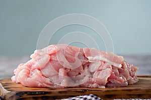 Raw pork loin cut into pieces on a wooden cutting board