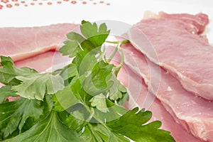 Raw pork loins and leaves of fresh parsley